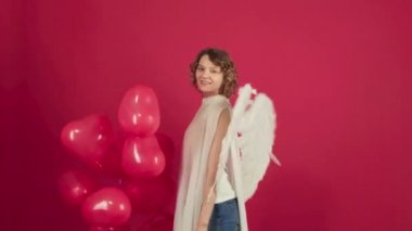 Sevgililer gününde genç bir kız. Sevgi. Sevgililer Günü 'nde randevusu olan romantik bir kadın. 14 Şubat. Kırmızı arka planda kırmızı kalp şekilli hava balonu olan sevgililer günü güzeli kız izole edilmiş..