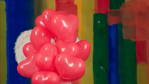 Mujer ángel bonita envía beso de aire con forma de corazón globo rojo sobre fondo de color. San Valentín niña ángel de belleza con globos de aire rojos y rosados en el fondo de color . — Vídeo de stock