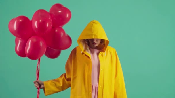 Sevgililer Günü 'nü kırmızı balonlarla kutlayan çılgın bir kadın. Yeşil üzerine sarı giyinmiş.. — Stok video