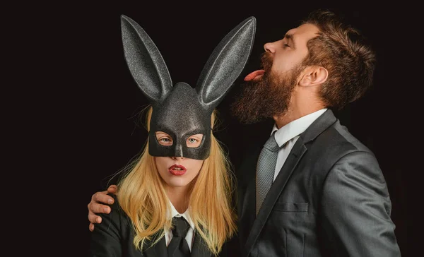 Konijnenmasker vrouw. Serieuze man met baard. Konijn en meisje. Mooie vrouw in konijnenkostuum. Stijlvolle man. jong meisje Pasen vrouw in konijn oren. — Stockfoto