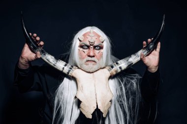 Cadılar Bayramı canavarı gibi giyinmiş yaşlı sakallı bir adam. Korku ve fantezi konsepti. Cehennemdeki Şeytan. Boynuzlu kötü adam. Yüzünde dikenler olan gizemli savaşçı..
