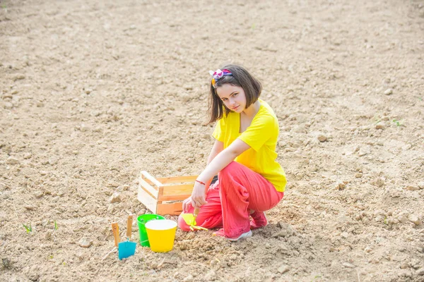 Маленький помощник в саду. Маленькая девочка-садовница и веселится на весеннем дворе. Дочь выращивает цветы. Посевные работы на полях . — стоковое фото
