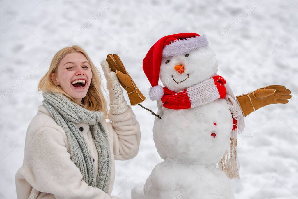 Christmas winter poeple. Greeting snowman. Winter scene with happy people on white snow background. Winter portrait of young woman in the winter snowy scenery.