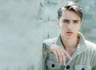 Kendine güvenen bir adamın portresi. Gri arka planda genç adamın yakın çekimi. Erkek moda konsepti.