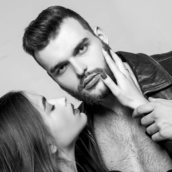 Toca-lhe na cerda. Ela adora barba masculina. Abraço apaixonado. Casal apaixonado no amor. Homem brutal bem preparado macho e menina atraente abraçando. Namorada apaixonada lábios vermelhos e jaqueta de couro homem — Fotografia de Stock