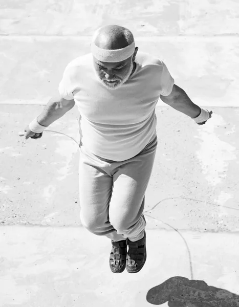 Sports old man doing exercises with jumping rope. Healthcare cheerful lifestyle. Age is no excuse to slack on your health.