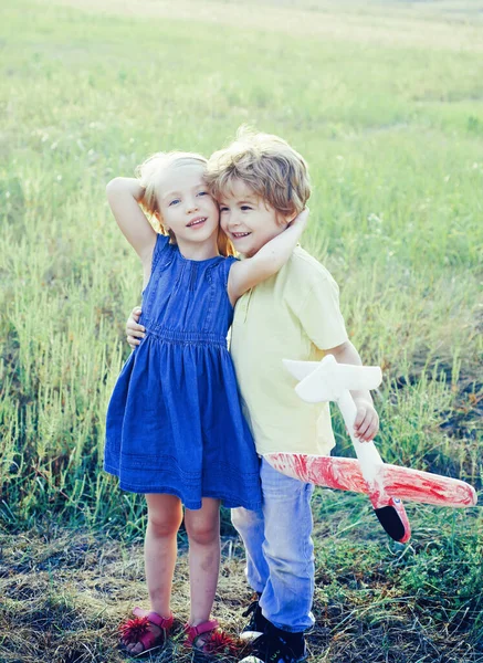 Leuke kinderen - dochter en zoon spelen met speelgoed vliegtuig in de wei in vintage kleur toon. Herinneringen aan de jeugd. Concept van dromen en reizen. Valentijnsdag. — Stockfoto