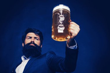 Yakışıklı barmen elinde bira tutuyor. Hipster barda diniyor. Bir bardak bira ile sakallı adam.