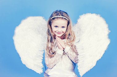 Angels little hands crossed for you. Mischievous little angel girl standing with your clenched fists.