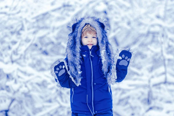 Vinterlandskap av skog och snö med söta barn pojke. Vinterungen poserar och har kul. Söt liten unge njuter i vinterparken i snö. — Stockfoto