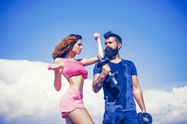 Beautiful brunette woman and bearded handsome man doing sport fitness activities at blue sky background. Attractive young couple do fitness exercises during their leisure time. — 스톡 사진