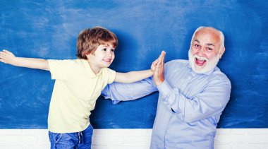 Teacher helping kids with their homework in classroom at school. Man teaches child. Happy Grandfather with his grandson to use a laptop.