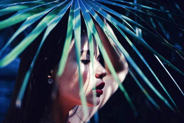 Vrouw met palmbomen. Schoonheid rode lippen make-up foto. Sensueel model meisje met gladde huid en make-up. Portret van jonge en mooie vrouw met een perfecte gladde huid in tropische bladeren. Zonnige dag. — Stockfoto