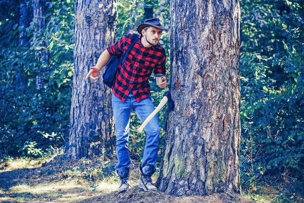 Lumberjack worker walking in the forest with axe. Handsome man with axe. Strong man lumberjack with an ax in a plaid shirt. Agriculture and forestry theme. — Stock Photo, Image