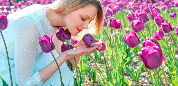 Mujer rubia en un campo de tulipanes sonriendo. Hermosa mujer morena con tulipanes en el campo de flores . — Foto de Stock
