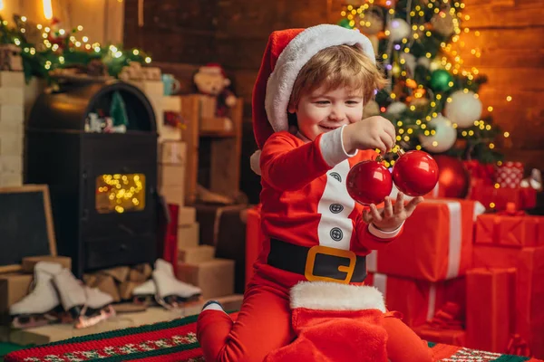 Niño feliz en la ropa de Santa celebrar bauble y la decoración del árbol de Navidad. Concepto de niño de Navidad. Ayudante de Santa niños . — Foto de Stock
