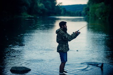 Fisherman relaxing while fishing on the lake at the morning. Luxury life concept. Guy fly fishing. Fishing requires to be mindful and fully present in moment. Start living.