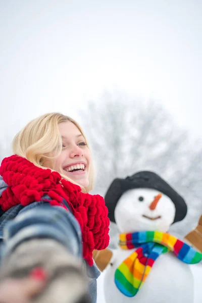 Snowman in snow forest. People in snow. Snowman and snow day. Winter portrait of young woman in the winter snowy scenery. — Stockfoto