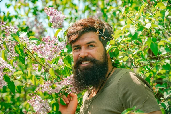 Handsome man spend time in the orchard. Portrait of bearded man against green spring field. I like spending time on farm. American boy in the farm on countryside background.