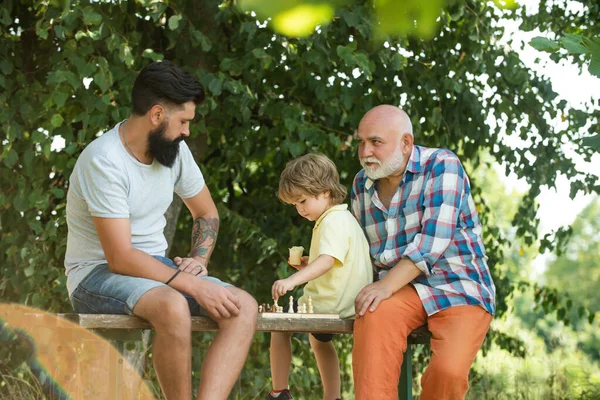 Idősebb férfi, aki sakkozni tanítja az unokáját. Imádom a sakkot. Családi generáció: a jövő álma és az emberek fogalma. Boldog család.. — Stock Fotó