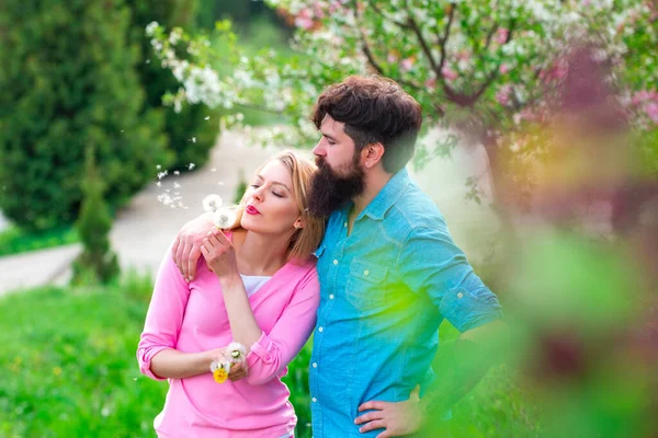 Hübsche Frau und schöner Mann, die im Frühlingspark spazieren gehen und die schöne Frühlingsblütennatur genießen. — Stockfoto