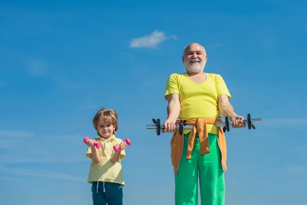 Enfant mignon et homme âgé faisant de l'exercice avec des haltères. Entraîneur sportif et renforcement des enfants avec haltères . — Photo