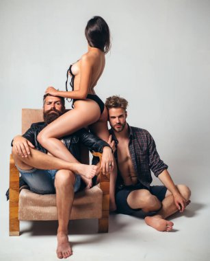 Seksi çıplak kadın iki yakışıklı sakallı adamla sevişiyor. Lüks koltukta grup seks oyunları. Arzu dolu bir kadın ve erkek, cinsel ilişki yaşayacaklar. Üç seksi partner..