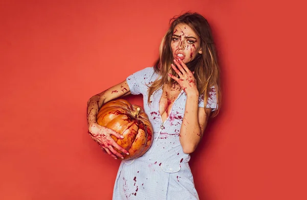 Beauty Halloween bloody woman on red background isolated. Girl with pumpkin. Blood on face. A terrible Halloween. — Stok fotoğraf