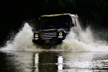 Off-road yarışında çamur ve su sıçraması. Gezgin off-road aracı. Sürüklenen yarış arabası lastik yakar. Aşırıya kaçmış. Off-road arabası.