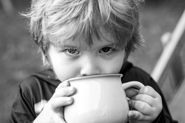 Bir şey içen çocuk. Küçük çocuk temiz havada eğleniyor. Doğada gülümseyen çocuk portresi.