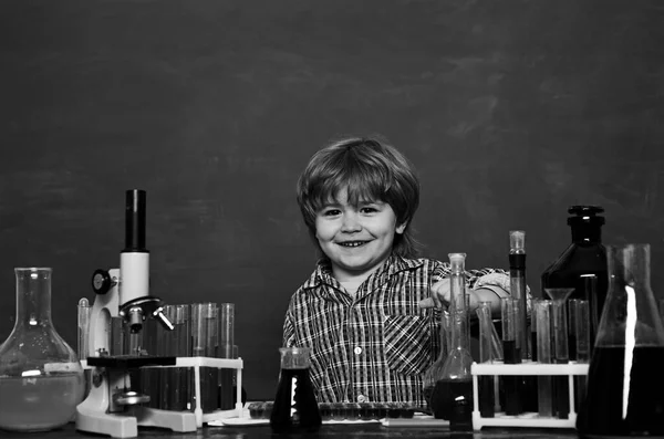 Chemistry lesson. My chemistry experiment. Happy smiling pupil drawing at the desk. Biology experiments with microscope. schoolchild