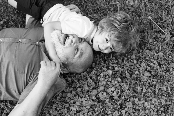 Abraço em grama verde - avô e neto. Feliz avô mais velho com o neto menino bonito brincando no parque. Criança feliz com o avô brincando ao ar livre . — Fotografia de Stock