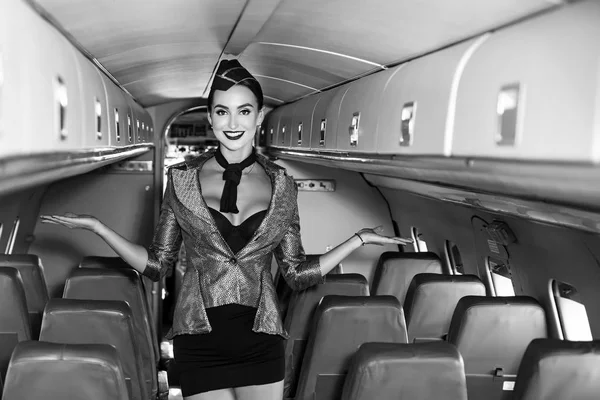 Mooie stewardess in een vliegtuigcabine glimlachend. Charmante stewardess gekleed in blauw uniform. Reisconcept. Aantrekkelijke stewardess van een jonge vrouw. Vliegtuig aan boord. — Stockfoto