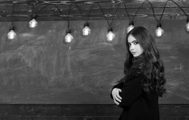 Genç çekici öğretmen tahtayı işaret ediyor. Önce eğitim. Öğrenci hayatı. Okula dön ve mutlu ol..