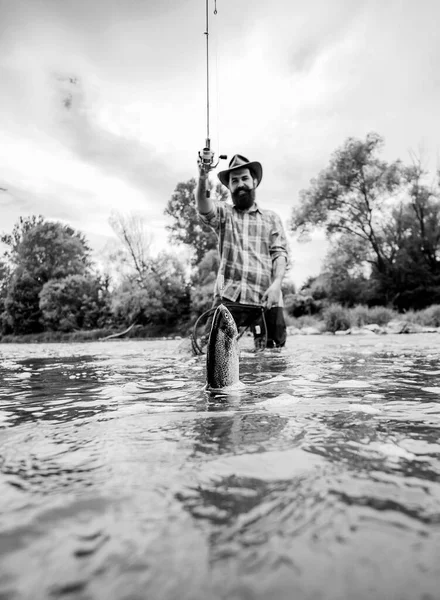 Hombre de pesca y relajarse mientras disfruta de hobby. Feliz pescador pescando en el río sosteniendo cañas de pescar. Trucha arco iris Steelhead. Trucha marrón atrapada en red de pesca . — Foto de Stock