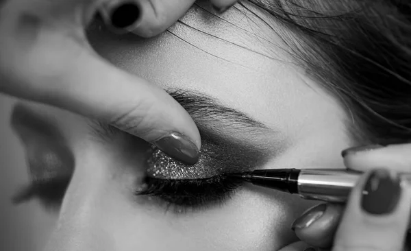 Retrato de close-up. Processo de fazer maquiagem. Um maquiador profissional pinta modelos de pestanas no estúdio. — Fotografia de Stock