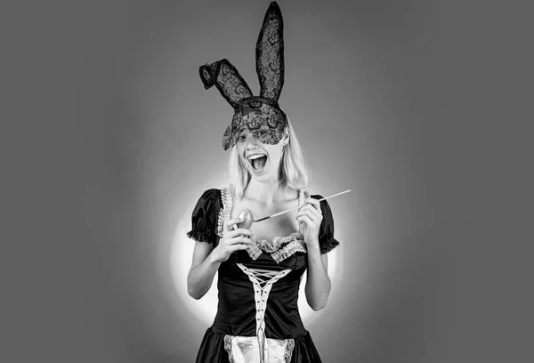 Sensuell kvinna är redo för påsklovet. Glad ung kvinna målning ägg på en fed bakgrund. Glad påsk. Söt kanin. — Stockfoto