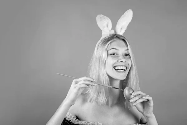 Prachtig sensueel blond. Vrolijke jonge vrouw die eieren schildert op een groene achtergrond. Blond meisje met konijnenoren en paaseieren. Konijntje. — Stockfoto