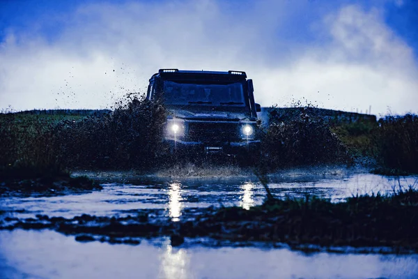 Kerék közelíti a vidéki táj egy sáros úton. Víz csobbanás az off road verseny. Terepjáró jármű jön ki a sár lyuk veszély. — Stock Fotó