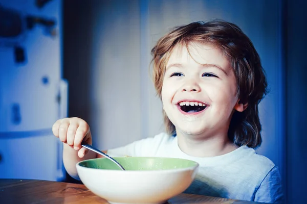 Kid eten. Kleine jongen met ontbijt in de keuken. Glimlachend gelukkig schattige baby eten fruit mash in de keuken. Hongerige kleine jongen eten. — Stockfoto