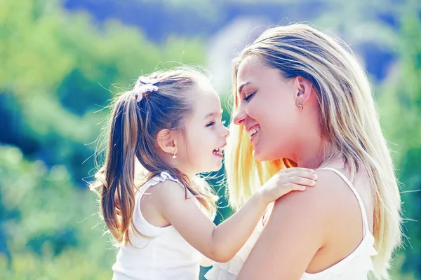 Amor infantil. La familia feliz y la mamá encantadora y la hija pasan el tiempo juntos - el día de las madres. Día de las madres. Madre e hija disfrutan y miran a la cámara. —  Fotos de Stock