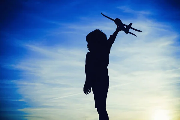 Black silhouette of cute happy child running at countryside and holding toy plane in hand. Happy childhood. Summer portrait of happy cute child. Enjoying life and nature. — Stock Photo, Image