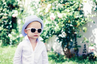 Çocuk dışarıda oynuyor. Mutlu anlar. Güneşli bir günde, güneş gözlüklü, gülümseyen küçük çocuk..