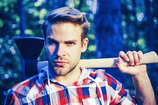 Un leñador con hacha en las manos. Un joven guapo con hacha cerca del bosque. La leña como fuente de energía renovable. Hombre haciendo trabajo de hombre. Descansando después del trabajo duro. —  Fotos de Stock