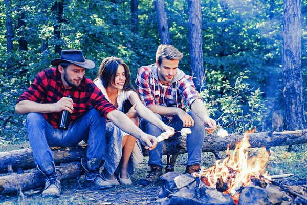 Os amigos gostam de churrasco de fim de semana na floresta. Amigos da empresa piquenique ou churrasco assando marshmallows perto da fogueira. Grupo de mochileiros relaxando perto da fogueira. Churrasco para assar marshmallows . — Fotografia de Stock