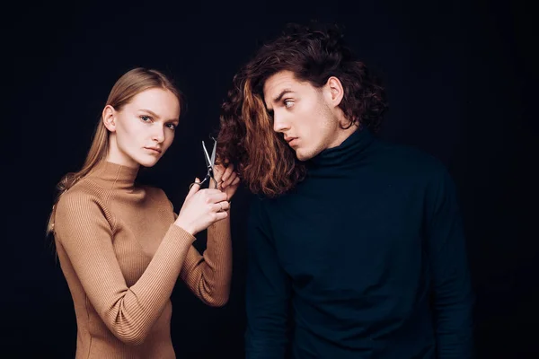 Femme avec des ciseaux va faire incroyable coupe de cheveux homme. Concept de salon de coiffure. Coiffeuse va couper les longs cheveux secs blanchis ondulés de l'homme client. Coiffure homme, bien-être et mode . — Photo