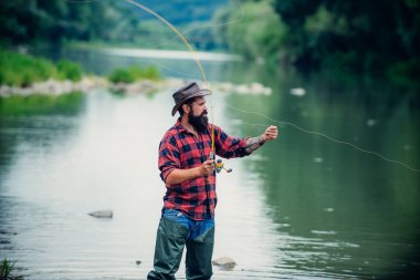 Fishing. Brutal man stand in river water. Man bearded fisher. Man fishing on the lake. Hobby for soul. Just do that only. Angler catching the fish. United with nature. Fly fishing.