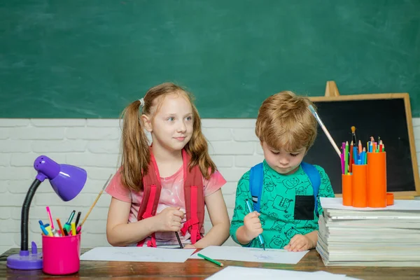 Zurück zur Schule. Kinderschule. glückliches nettes fleißiges Kind sitzt an einem Schreibtisch drinnen. Bildungsprozess. — Stockfoto