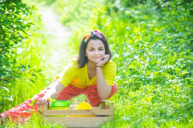 Portrait of kid gardener carrying harvested in farm. Child spend time in the orchard. Child farmer in the farm with countryside background.