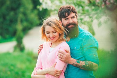 Baharda çiçek açan parkta yürüyen aşıklar. Güzel mutlu çiftin bahar portresi. Güneşli bir günde bahar parkında gülümseyen mutlu çift. Seni seviyorum..